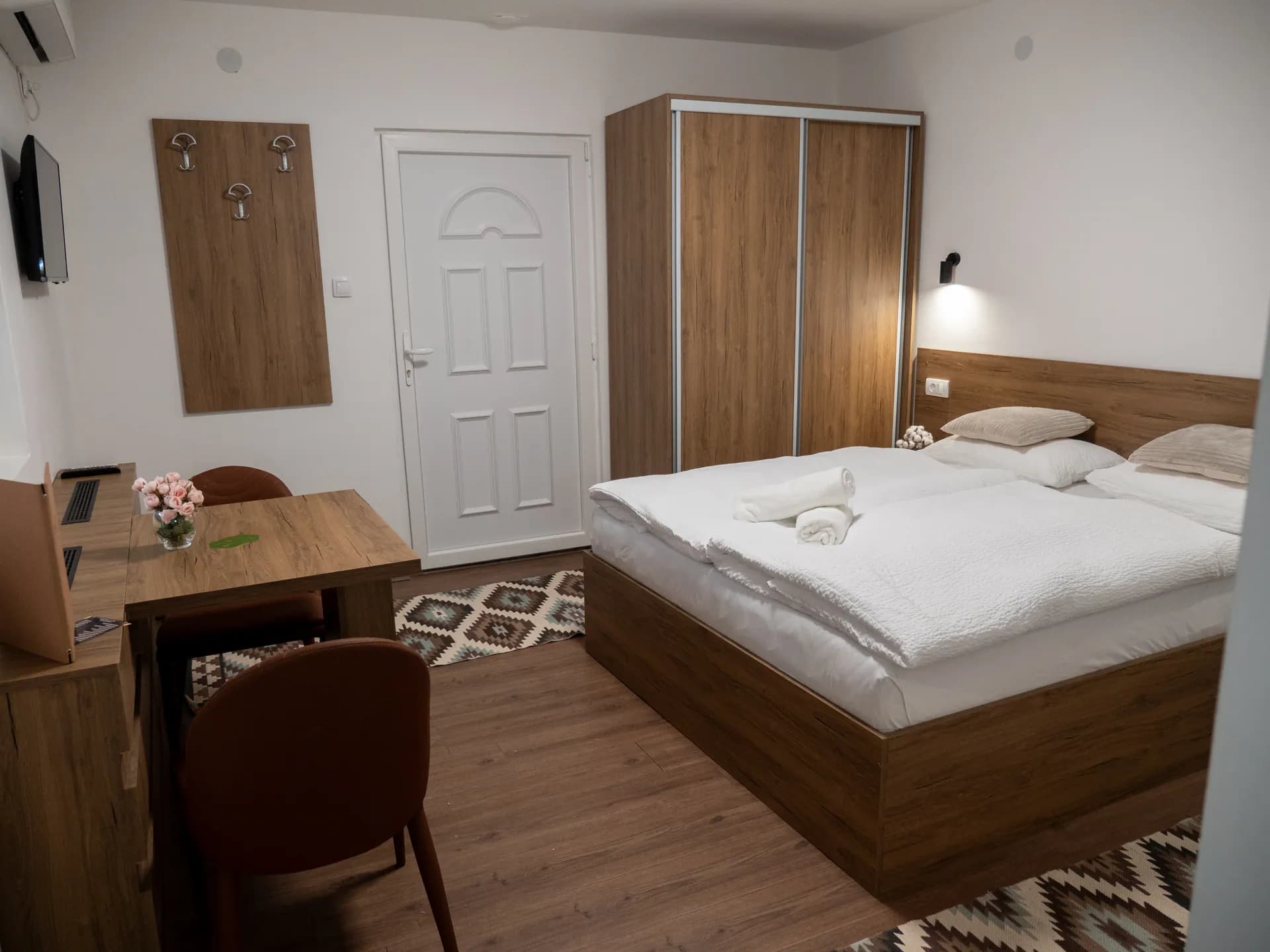Apartment I — a table with two chairs, coat hooks, a wardrobe with sliding doors and the bed