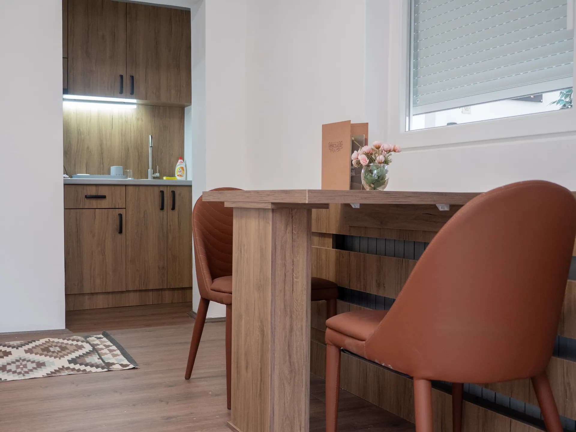 Apartman I — trpezarijski sto sa dve stolice, iza njega čajna kuhinja