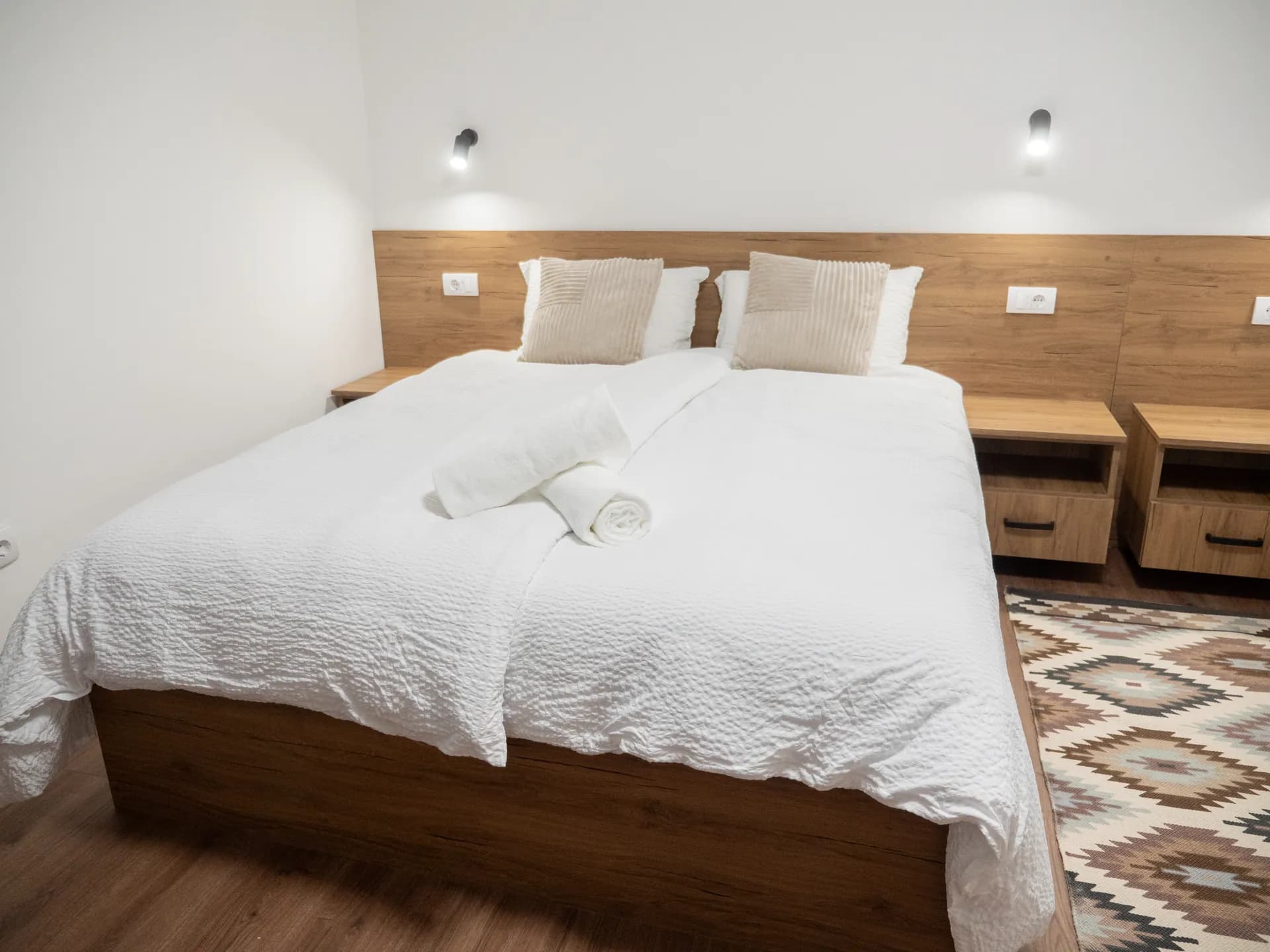 Apartment II — a double bed with a wooden headboard and two bedside tables