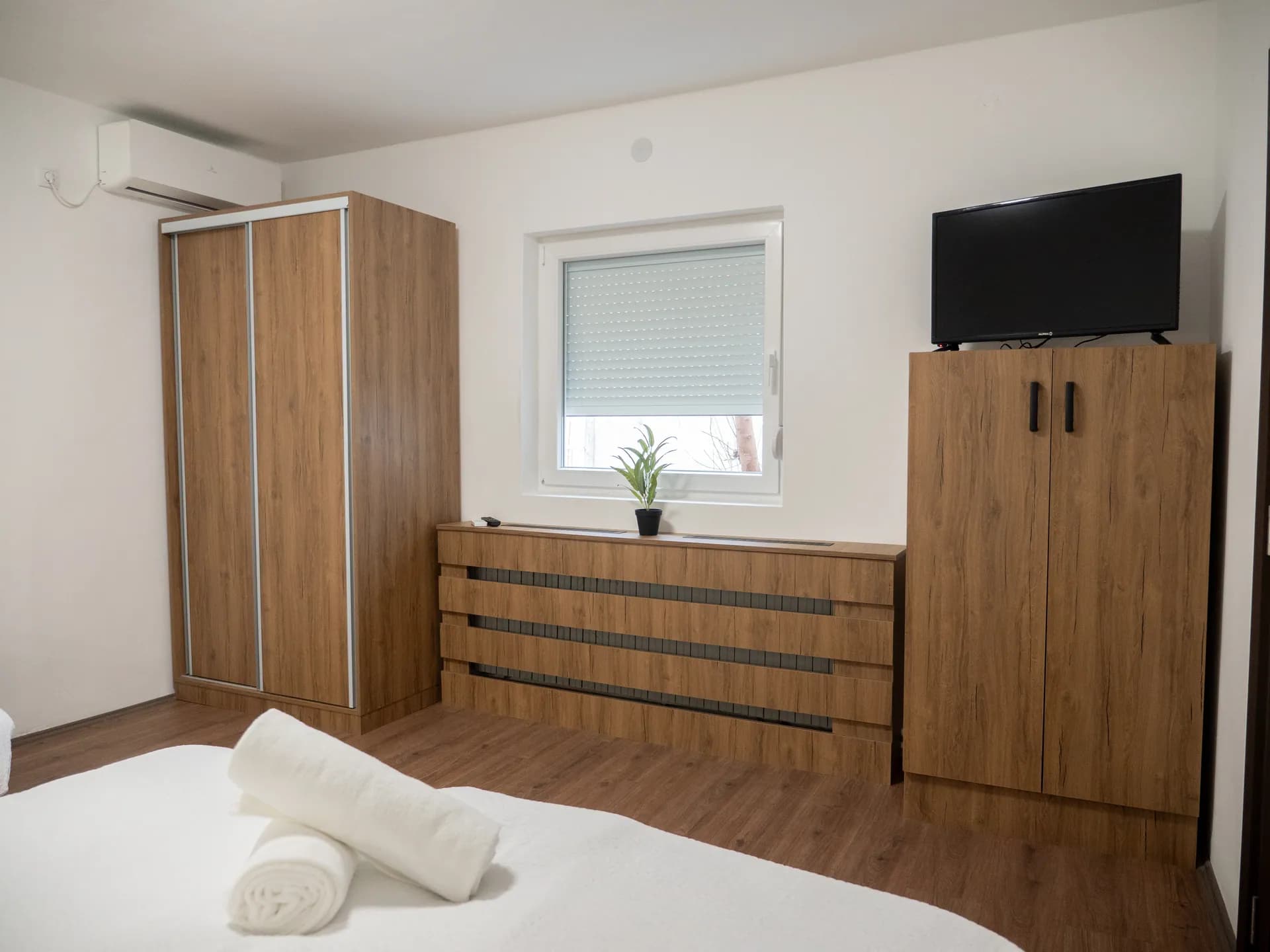 Apartment II — a wardrobe with sliding doors, a TV and a window with a roller blind