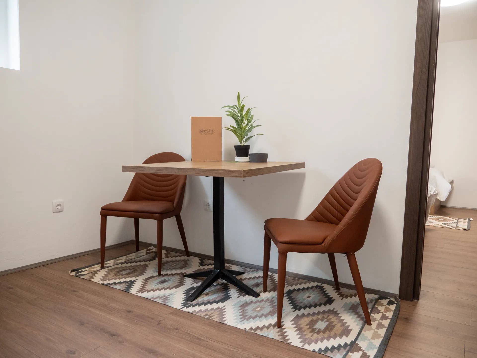 Apartment II — a table with two chairs on a woven rug