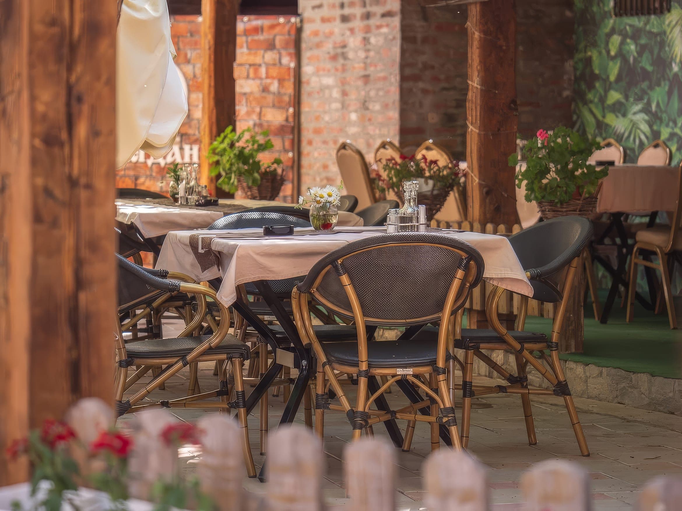 Detalj bašte Restorana Megdan — sto sa poljskim cvećem i pletene stolice